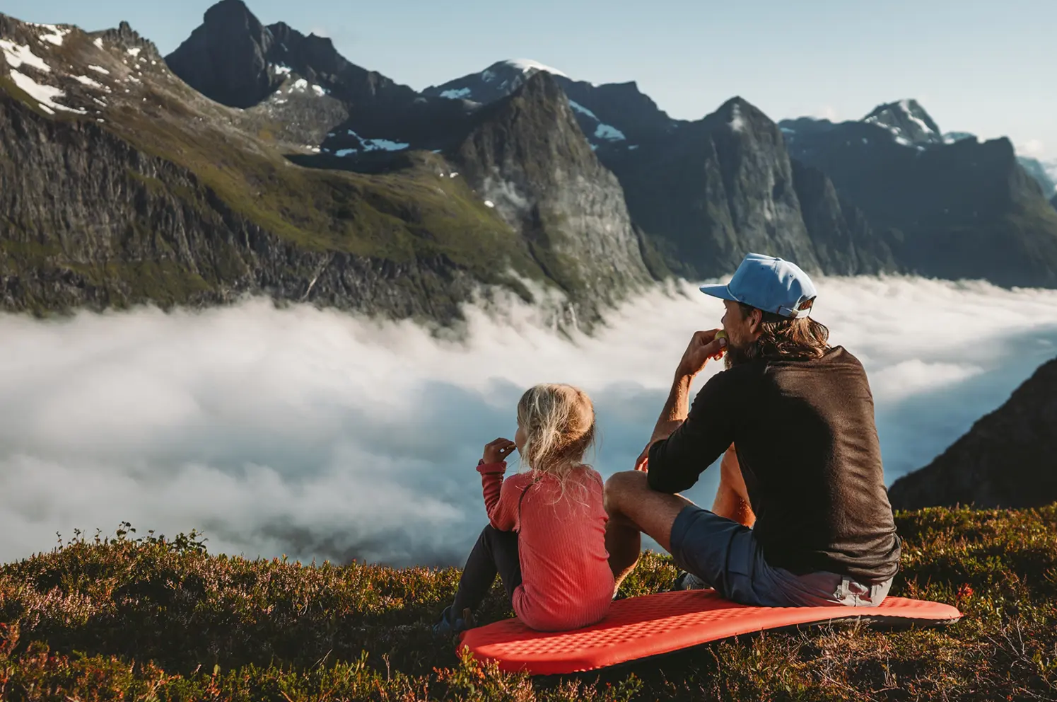 Father and daughter eating snacks in the mountains